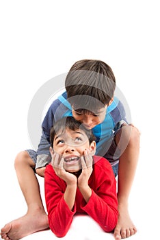 Little sibling boys sit and play together on white background