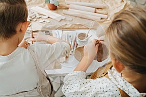 Little siblings working with clay in a workshop, cutting and shaping it