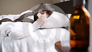 Little sick boy in the bed with kleenex sneezing
