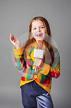 Little singer girl. Little girl with microphone over grey background.