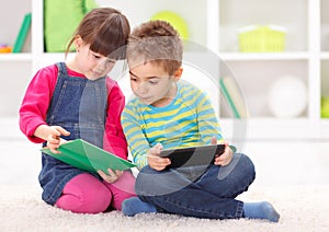 Little sister and brother reading from an interesting book