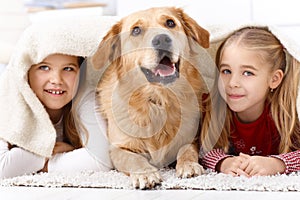 Little sisters and pet dog at home smiling