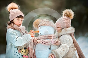 Little sisters with snowman