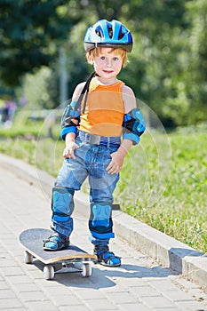 Little skateboarder stands on park alley with one