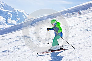 Little skier riding downhill in high mountains