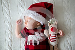 Little sleeping newborn baby boy, wearing Santa hat