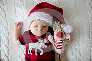 Little sleeping newborn baby boy, wearing Santa hat