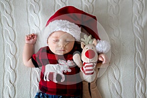 Little sleeping newborn baby boy, wearing Santa hat