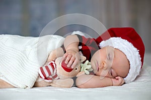 Little sleeping newborn baby boy, wearing Santa hat