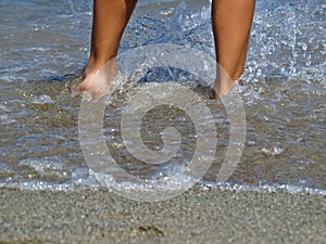 Little Small Child Legs in Water on Sandy Beach Relaxing and Standing During Summer Vacation