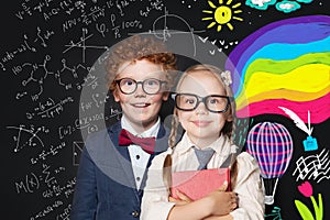 Little smart boy and girl on blackboard background with science formulas and arts pattern. Back to school concept