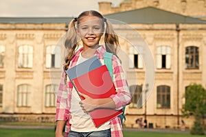little smart student. happy preschool girl with folder in school yard. back to school. hardworking child with book