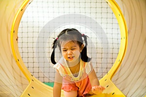 A little smile girl is crawling out of yellow tunnel at playground