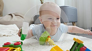 Little smiling baby boy palying and having fun with toy blocks and toy on floor at living room. Concept of children