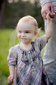 Little smiling baby holding father's hand