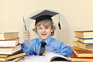 Little smiling boy in academic hat with rarity pen among old books photo