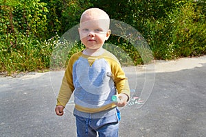 Little smiling boy holds colorful chalk for drawing in hand on a summer day. Children`s activity