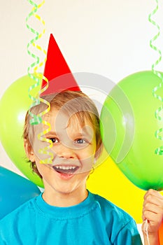 Little smiling boy in holiday hat with festive balls and streamer