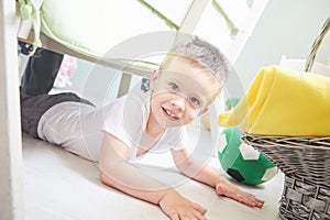 Little smiling boy is lying on a floor at home.