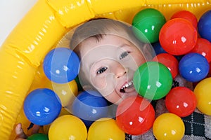 Little smiling boy playing in colorful balls playground