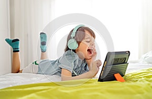 Little smiling boy playing on a digital tablet at home.