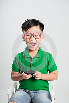 Little smiling child boy playing games or surfing internet on digital smartphone computer