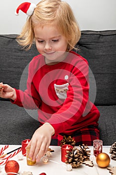 Little smiling child wearing christmas holiday pajamas, doing crafts Christmas tree decorations.