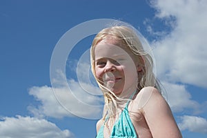 Little smiling girl against sky in summer