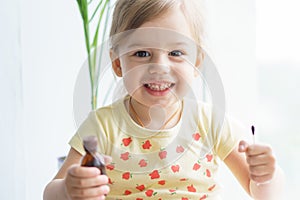 Little smiling girl holding a medicine jar of iodine and an ear stick in her hands. Treatment of rashes, acne, pimples