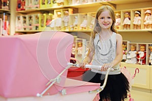 Little smiling girl holds handle of big pink