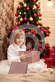 Little smiling girl opens a magic Christmas gift box
