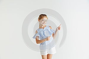 Little smiling girl posing in casual clothes on white studio background