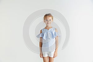 Little smiling girl posing in casual clothes on white studio background