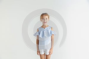 Little smiling girl posing in casual clothes on white studio background