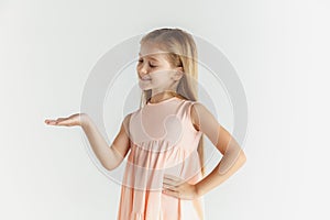 Little smiling girl posing in dress on white studio background