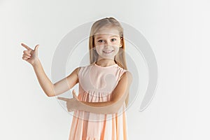 Little smiling girl posing in dress on white studio background