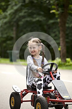 Little smiling girl in racing car amusemant park