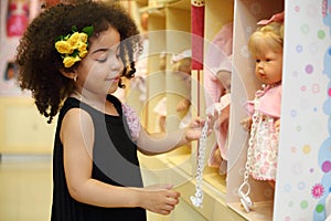 Little smiling girl touches dummy of toy doll in