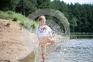 Happy child playing in the lake. Kid having fun outdoors