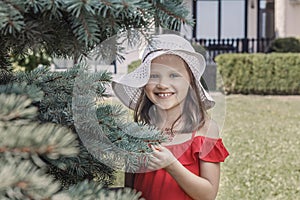Little smiling girl in a white hat and red dress