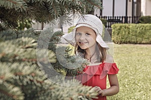 Little smiling girl in a white hat and red dress