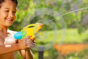 Little smiling happy boy shooting water gun