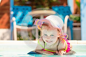 Little smiling pleasured blond girl lying in front of the water