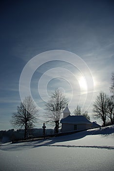 Little snow-bound chapel before sunset