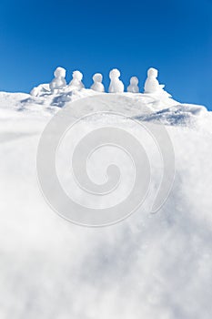 Little snowmen figures standing on a mountaintop, copyspace in t