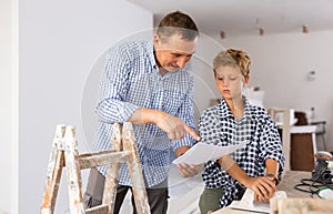 Little son with father together checking blueprints before renovating room