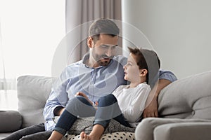 Little son having confidence conversation with father at home