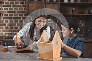 Little son and his beautiful mother crafting a wooden birdhouse