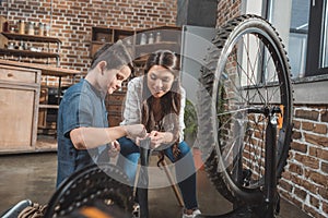 Little son and his beautiful mother fixing a deflated bicycle tire