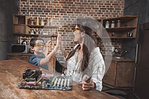 Little son and his beautiful mother high-fiving while working on a computer motherboard